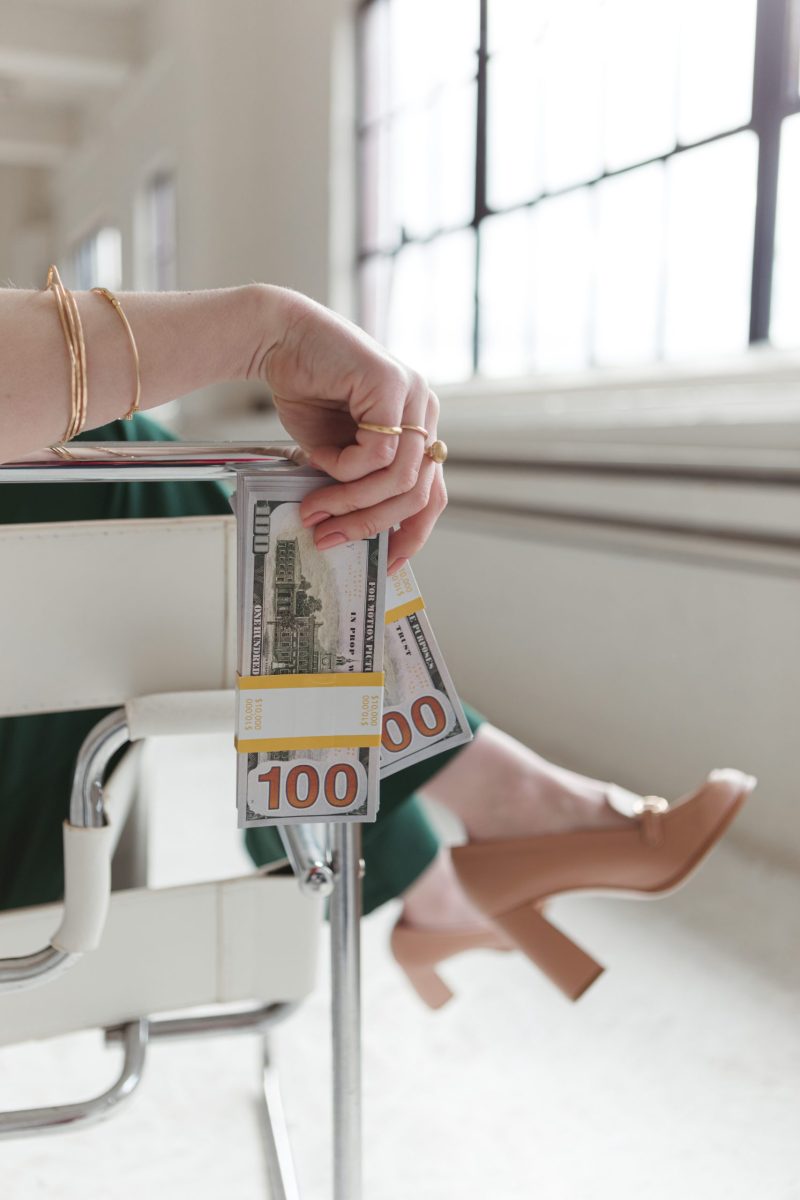 jillian minter heels and money Close-up of a woman's legs in high heels holding hundred-dollar bills, symbolizing wealth and confidence.