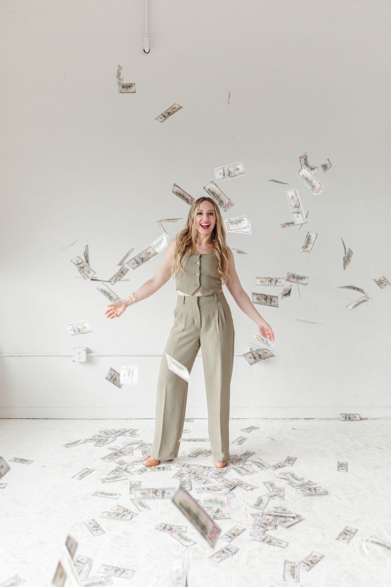 Jillian Minter money flying around Jillian, a smiling money coach, tossing cash in the air with radiant confidence and abundant energy.