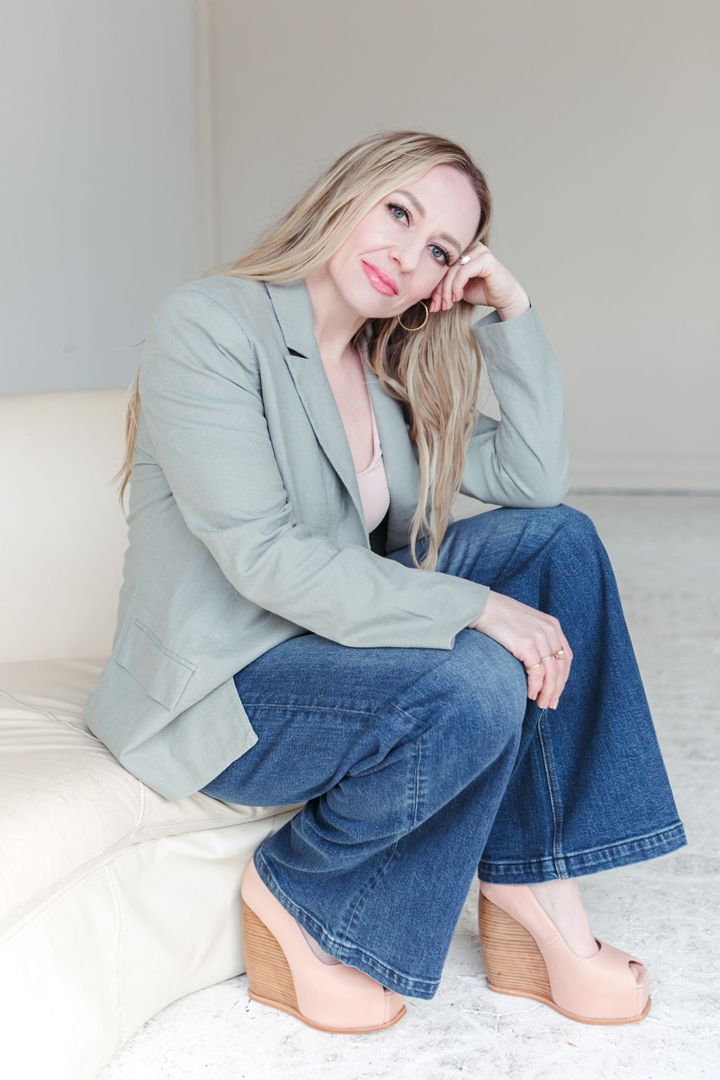 jillianminter-49 A woman in a deep green sleeveless jumpsuit sits on the floor counting multiple stacks of $100 bills, with scattered cash surrounding her. Her relaxed posture and confident handling of the money evoke abundance, financial empowerment, and wealth coaching vibes.